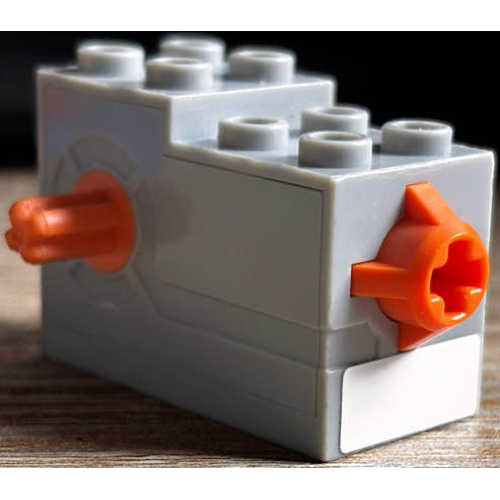 Деталь LEGO 61100c01pb01 Windup Motor 2 x 4 x 2 1/3 with Orange Axle and Release Button with White Rectangle Pattern (Sticker) - Set 7738